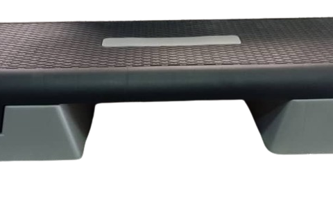 A commercial-grade step board designed for fitness training. The board features a sturdy, rectangular frame with non-slip surface and adjustable height options. It is placed on a gym floor with weights and other fitness equipment visible in the background